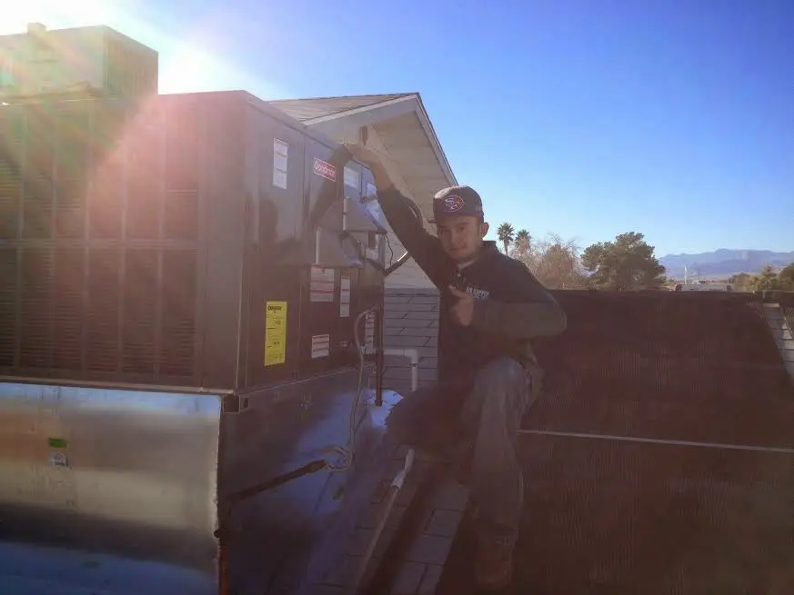 HVAC technician performing AC Tune-Up on a rooftop unit in DeKalb